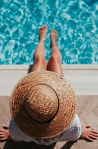 photo de femme les pieds dans l'eau avec un chapeau de paille